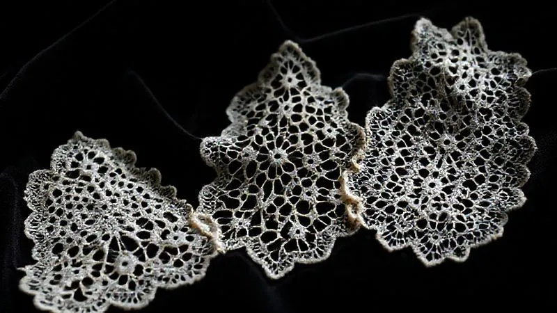 A close-up, photorealistic shot of three distinct samples of vintage lace, each with unique patterns and textures, meticulously arranged on a dark velvet cloth under soft, museum-like spotlighting. One appears hand-stitched, another machine-made, and a third shows signs of age and delicate repair. Professional photography, 8K, cinematic lighting, sharp focus, depth of field, shot on a high-end DSLR.