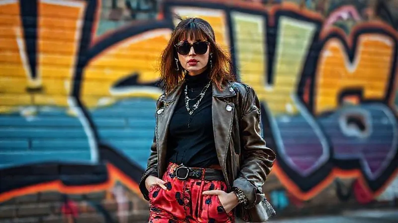 A fashion blogger, with a unique, artistic sense of style, is captured in a dynamic pose, their outfit perfectly blending with a vibrant, urban street art mural in the background. The image emphasizes storytelling through fashion and setting. Photorealistic, professional photography, 8K, cinematic lighting, sharp focus on the blogger, depth of field blurring the mural slightly, shot on a high-end DSLR, emotionally resonant with creativity and individuality.