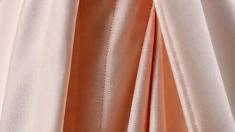 A close-up, detailed shot of a garment showcasing strategic princess seams, well-placed darts, and subtle ruching. The fabric drapes elegantly, highlighting the internal construction that flatters the figure. Photorealistic, professional photography, 8K, cinematic lighting, sharp focus on the garment details, depth of field blurring the background, shot on a high-end DSLR.