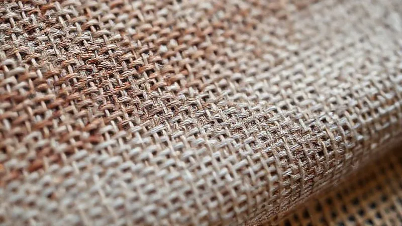 A macro shot, photorealistic, professional photography, 8K, cinematic lighting, sharp focus, depth of field, shot on a high-end DSLR, showing the intricate, irregular weave of a hand-loomed silk fabric from the 1920s, with subtle imperfections, contrasting with the uniform, machine-made texture of a modern synthetic fabric.