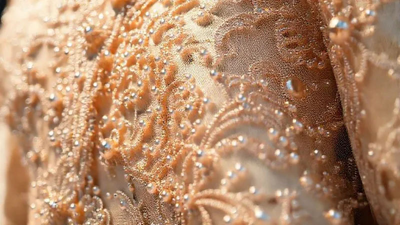 A close-up, photorealistic image of a haute couture garment featuring incredibly intricate, multi-layered hand-embroidery with delicate beads and sequins, catching cinematic light. The textile itself appears rich and unique, perhaps a woven silk or jacquard. Sharp focus on the detailed craftsmanship, with a soft depth of field. Shot on a high-end DSLR, 8K hyper-detailed, professional photography.
