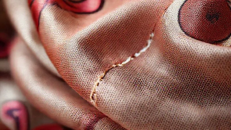 Close-up of a perfectly executed invisible mend on a vintage silk scarf, showcasing the seamless repair, with natural light highlighting the texture, photorealistic, professional photography, 8K, cinematic lighting, sharp focus, depth of field, shot on a high-end DSLR.