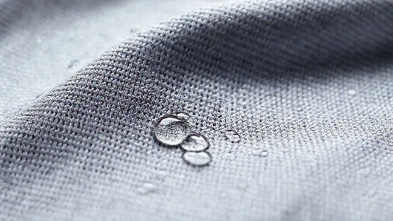 Photorealistic, professional photography, 8K, cinematic lighting, sharp focus, depth of field, shot on a high-end DSLR of a highly textured, moisture-wicking activewear fabric under magnification, showing intricate fiber structure and tiny water droplets being actively pulled away from the surface, conveying advanced textile technology.