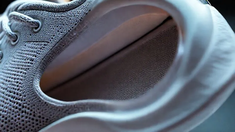 Photorealistic, professional photography, 8K, cinematic lighting, sharp focus, depth of field, shot on a high-end DSLR. A close-up, cutaway view of an athletic shoe's upper, clearly showing seamless, heat-welded layers of advanced materials. There are no visible stitches, only smooth, fused transitions between different textiles and translucent films, demonstrating sophisticated bonding technology. The internal structure is visible, revealing lightweight, supportive elements.