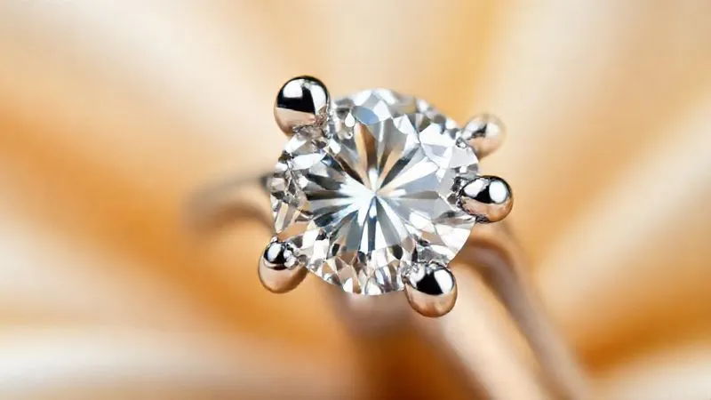 A macro, close-up shot of a high-value diamond ring, focusing on a single platinum prong that is visibly bent and pulled away from the diamond, creating a precarious gap. The diamond itself is slightly askew within the setting. The image is photorealistic, professional photography, 8K, cinematic lighting, sharp focus on the damaged prong, depth of field blurring the rest of the ring, shot on a high-end DSLR.
